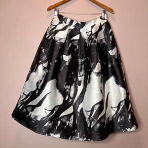 ANGL black and white printed silk midi skirt, often styled as a flowy pleated sk